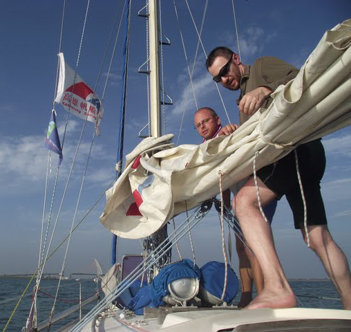 Kapitán s plavčíkem skládají hlavní plachtu.